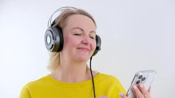 mujer en auriculares bailando escuchando a música alegría agradable emociones bueno hora musicalidad bailando en un brillante naranja traje levantamiento Cejas en un blanco antecedentes laminación su ojos blanco manicura rubia video