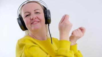 in real time real people woman dancing to music with headphones opens her mouth laughs blonde waving her head and arms on a white background having fun fast music bright clothes video