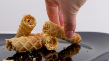 gaufre Rouleaux délicieux croustillant pâte brisée Pâtisserie dans cuisson tubes avec condensé Lait bouilli condensé Lait à l'intérieur le dessert femelle mains Pause en haut les miettes et parfumé douceur sur une noir assiette video