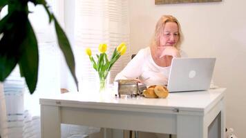 Frau Sitzung im Zimmer reden auf Telefon auf Laptop Arbeiten Trinken Kaffee freiberuflich Arbeit online Studie Freizeit chatten mit freunde angenehm Morgen Täglich Prozess Denken träumend wunderbar Leben video