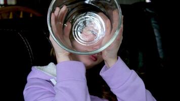 meisje spelen met glas fles tiener meisje op zoek door het uitpuilend ogen opening mond schattig jong vrouw voor de gek houden in de omgeving van hebben pret lachend op zoek door glas jong gezicht lila blouse donker kamer video