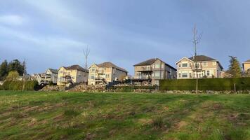 view of the private sector On a high hill, identical beautiful three-story houses mansions in the city of Surrey Vancouver Canada blue sky and green grass halving space for text housing for the rich video