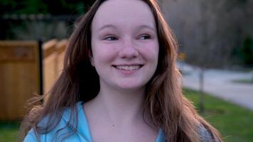 A young girl waves her hands at herself on a hot sunny day in the evening, blue jacket, European, long hair, smiling video