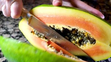 woman hands cutting a papaya in half. sharp knife to carefully slice video