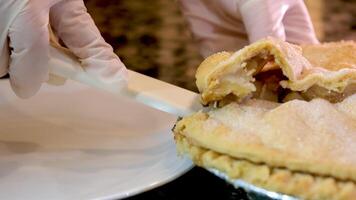 cut apple pie with knife on wooden background, close up video