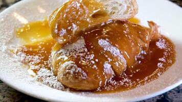 delicioso cuerno en un blanco plato vertido con caramelo jarabe jarabe se extiende en diferente direcciones en polvo azúcar sabroso apetitoso también dulce francés postre para té para café servicio comida almuerzo video