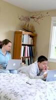 Two caucasian children watching something funny on laptop. Attractive brunette boy pointing his hand on screen. Pretty little girl laughing from what she see on computer video