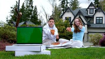 friends ordered pizza to take home laptop with green screen chroma key thumb up open box place for text ad pizzeria sit on grass picnic near house teenagers schoolchildren spend time together video