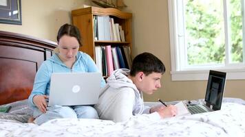 Two caucasian children watching something funny on laptop. Attractive brunette boy pointing his hand on screen. Pretty little girl laughing from what she see on computer video