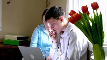 zwei kaukasisch Kinder Aufpassen etwas komisch auf Laptop. attraktiv Brünette Junge zeigen seine Hand auf Bildschirm. ziemlich wenig Mädchen Lachen von Was sie sehen auf Computer video