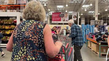Costco Wholesale Shopping cart movement in the store go to the checkout shop on a weekend products in huge cart children sitting on shopping baskets cart with whole family go to supermarket video