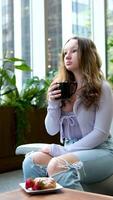 jovem mulher encantadora ligando com o telefone celular enquanto está sentada sozinha na cafeteria durante o tempo livre, mulher atraente com um sorriso fofo conversando com o celular enquanto descansa no café video