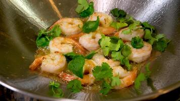 Male cook puts shrimp in frying pan with cooking oil, sprinkles salt. The chef cooks delicious dish. Cooking process on restaurant or cafe kitchen. Professional gourmet cuisine. Public catering. video