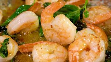 Male cook puts shrimp in frying pan with cooking oil, sprinkles salt. The chef cooks delicious dish. Cooking process on restaurant or cafe kitchen. Professional gourmet cuisine. Public catering. video