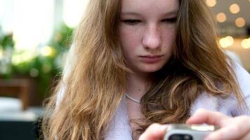 vrouw is typen een bericht Aan mobiel telefoon zittend en aan het wachten iemand in cafe. video