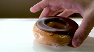 mettre une rond Donut avec une trou couvert avec Chocolat glaçage sur une blanc assiette fermer main met dans le centre de assiette une délicieux dessert réflexion comme dans miroir texte au lieu de menu publicité video