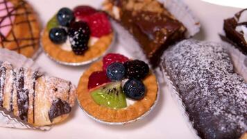 Buffet Portion Dessert köstlich Süßigkeiten von verschiedene Arten mit Schokolade Weiß Glasur pulverisiert Zucker Sahne auf das Tabelle Nahansicht schleppend Bewegung von ein Vielfalt von Nachspeisen video