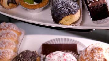 bufê servindo sobremesa delicioso doces do vários tipos com chocolate branco geada em pó açúcar creme em a mesa fechar-se lento movimento do uma variedade do sobremesas video