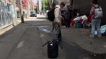 Canada, Vancouver, 04.04.2024 mensen mannen en Dames liggen Aan de bestrating staand in een donker steeg met rugzakken leven van dakloos mensen in een groot stad Vancouver straat downtown oostzijde Canada 2023 video