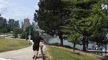 apresurándose calle Vancouver un hombre en un bicicleta en contra el antecedentes de un pintado pared en ivan kuvére fuma cigarrillos fármaco antiguo ropa gorra pantalones cortos verano calle en Vagabundo desempleados desempleo culo video