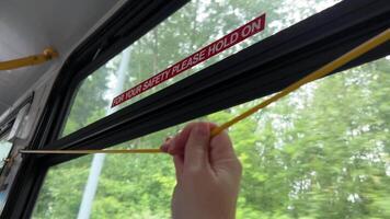 To stop Canadian buses, you need to pull rope, wire will sound stop signal, woman's hand stops bus, press sign, exit, end the journey, green leaves outside the bus window, Vancouver Canada, Surrey. video