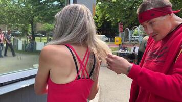 taglio capelli nel estremo condizioni senza casa persone fare loro capelli a un' memorizzare finestra con forbici uomo taglio via vecchio finisce di compagno bionda capelli rosso Abiti nel mani forbici disoccupato persone video