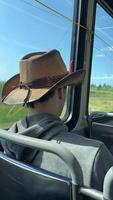 a man in a hat sits in a bus passing by a field cowboy headdress hooded sweatshirt a young man having fun going for a walk choosing clothes preference macho male style Canada Vancouver video