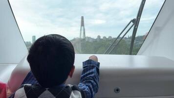 poco ragazzo sembra avanti a montagna nel skytrain puntamento il suo dito in il distanza trasporto per bambini famiglia turismo video