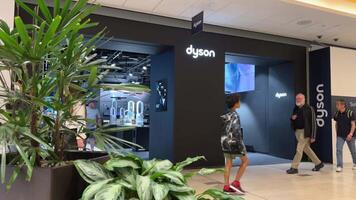 dyson rons. vacuum cleaners and other equipment inside a home appliance store a girl walks around the store looking at the latest technology in the hands of the girl bags of lLuluemon video