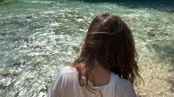 een meisje in een wit overhemd daalt af naar schoon voorjaar water bezienswaardigheden bekijken in Albanië saranda bystritsa rivier- Doorzichtig water blauw oog bezienswaardigheden bekijken reis bezienswaardigheden bekijken plaatsen vermeld in UNESCO natuur zomer reizen video