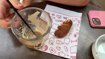 Bits auf das Tabelle leeren zu ein schmutzig Kaffee Becher ein Stück von Croissant und ein Telefon Frühstück ist Über nicht gereinigt schmutzig das Mädchen Hand stört mit das sich ausruhen von das Kaffee im ein Glas von Latté Cappuccino video