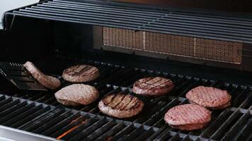 rundvlees hamburgers en spatel Aan de heet vlammend bbq houtskool grill, detailopname, top visie video