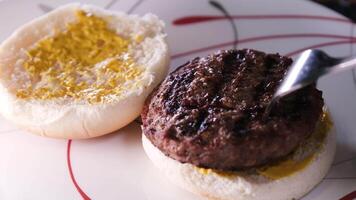 processo do preparando uma hamburguer americano Comida velozes Comida às casa pão mostarda colocar a costeleta espalhar a molho pressione a pão colocar a tomate adicionar ketchup video