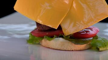 el cocinero viene a el mesa y pone un delicioso hamburguesa, manos en negro guantes. nutritivo desayuno. video