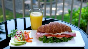on the street on the table breakfast croissant with meat and cheese tomato avocado salad radishes red pepper cilantro glass of orange juice on the balcony in a restaurant private lunch video