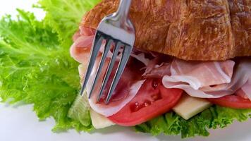 croissant smörgås med kött jamon skinka med tomat sallad mat rik bitar av ost i frukost Frankrike på en vit tallrik dyr restaurang hotell få en bit av kött med en gaffel video