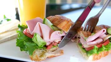 Close up with male's hands use a fork and knife to cut croissants for eating. video