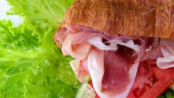 croissant sanduíche com carne jamon prosciutto com tomate alface Comida rico peças do queijo dentro café da manhã França em uma branco prato caro restaurante hotel obtendo uma peça do carne com uma garfo video