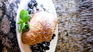 Extreme close up powdered sugar is poured onto croissants with blueberry. strainer with flour or sugar, which is sprinkled with baked goods before serving. Breakfast or dessert cooking concept video