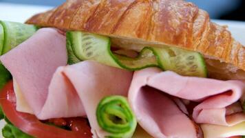 croissant med balyk och gurka sallad löv tomat utsökt frukost med ost och orange juice vit tallrik bacon skikten i smörgås på de balkong på svart tabell utsökt mat lunch mellanmål video