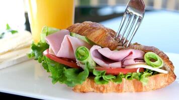 croissant with balyk and cucumber Lettuce leaves tomato delicious breakfast with cheese and orange juice white plate bacon layers in sandwich on the balcony on Black table delicious food lunch snack video