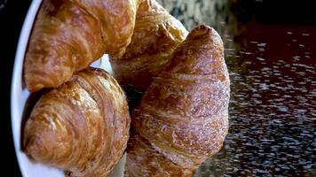 dolly sparo, vicino su, spruzzatina glassatura zucchero al di sopra di dolce brioche, posto su un' nero marmo lastra preparare per servire con caldo nero caffè. video