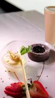 chocolate fundente em uma branco prato com Sombrio chocolate gelo creme morangos gotas do xarope lindo servindo dentro a caro restaurante sobremesa Comida video