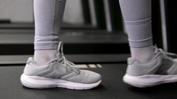 Young woman going on treadmill machine in fitness club. Close up on feet. High quality 4k footage video