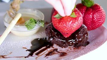 Eating brownie with fork. Taking bite of chocolate cake with chocolate icing and strawberries video