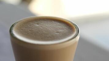 bebida en un vaso taza grueso espuma de cerca ventana reflexión en el mesa Dom rayos bonito día sentar en el sombra disfrutar latté café capuchino video