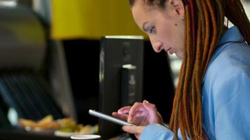 de cerca retrato de un joven bonito mujer con elegante azul rastas, utilizando teléfono inteligente a hogar, comprobación social medios de comunicación contenido, escritura texto mensaje, surf neto, en línea comunicación video