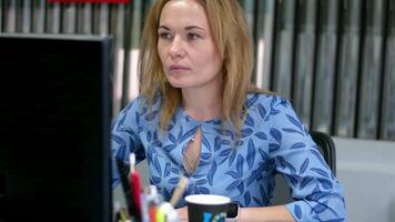 Close up of a woman looking at a laptop screen whilst working in an office video