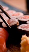 des bâtons prendre Sushi dans restaurant lumières Contexte. variété de les types Sushi avec rouge caviar, poisson, crême Philadelphia fromage et baguettes fermer. ensemble de délicieux Japonais Sushi Rouleaux sur une pierre planche video