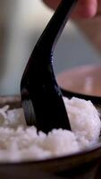 Spoon stir cooked white Thai jasmine rice in a rice cooker bowl close up. video